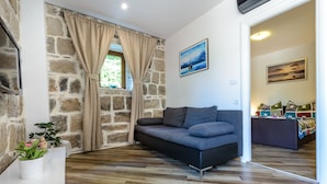 A cozy room with a stone wall, a sofa, a potted plant, and a painting on the wall.