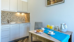 A modern kitchen with white cabinets, a stone backsplash, and a dining area with a table set for breakfast.