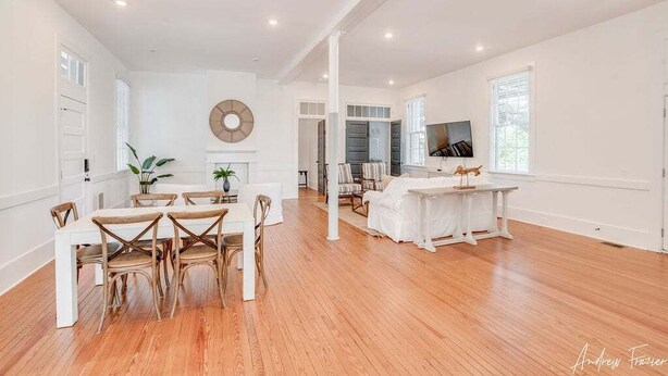 A spacious living area with a dining table and chairs, a fireplace, and a television.
