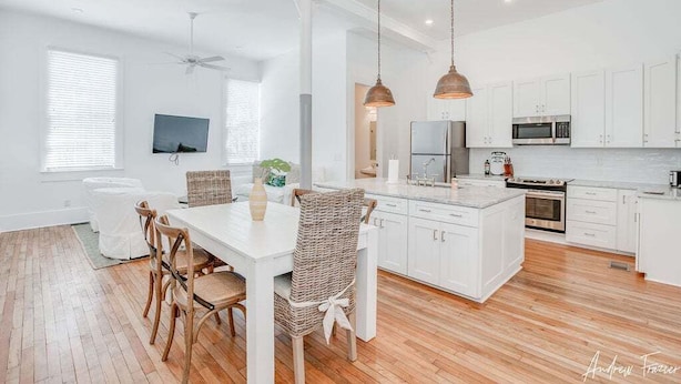 A modern kitchen with white cabinetry, a central island, and pendant lighting.