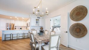 Una cocina amplia con una isla central, muebles blancos y una araña.