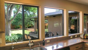 A kitchen with large windows, a sink, and a countertop with a fruit bowl. - Fabulous Red Rock Views, Private Outdoor Space, Hot Tub and Large Fenced Yard. (Sedona)