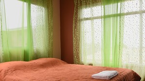 Une chambre avec un lit, des rideaux verts et une fenêtre donnant sur un beau paysage.