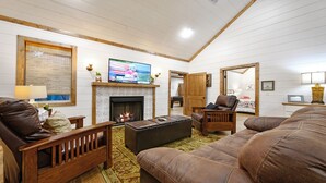 Un salon chaleureux avec une cheminée, des fauteuils confortables et un téléviseur.