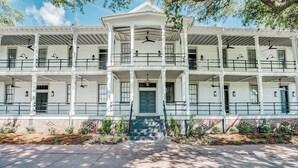 A two-story building with a central entrance, balconies, and a covered porch. - 2 King Bedrooms in Historic Barracks at North Beach (Tybee Island)