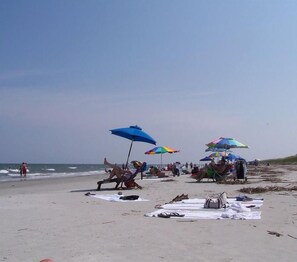 Een strand met parasols, handdoeken en mensen die ontspannen.