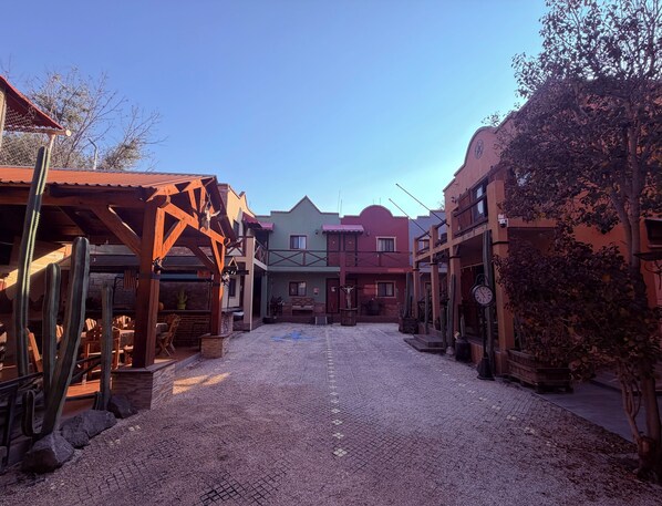 A courtyard with cobblestone ground, wooden buildings, and cacti. - Hotel West Refugio (San Juan del Río)