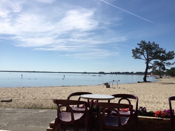 Vista de la playa con arena, algunas sillas y una mesa.