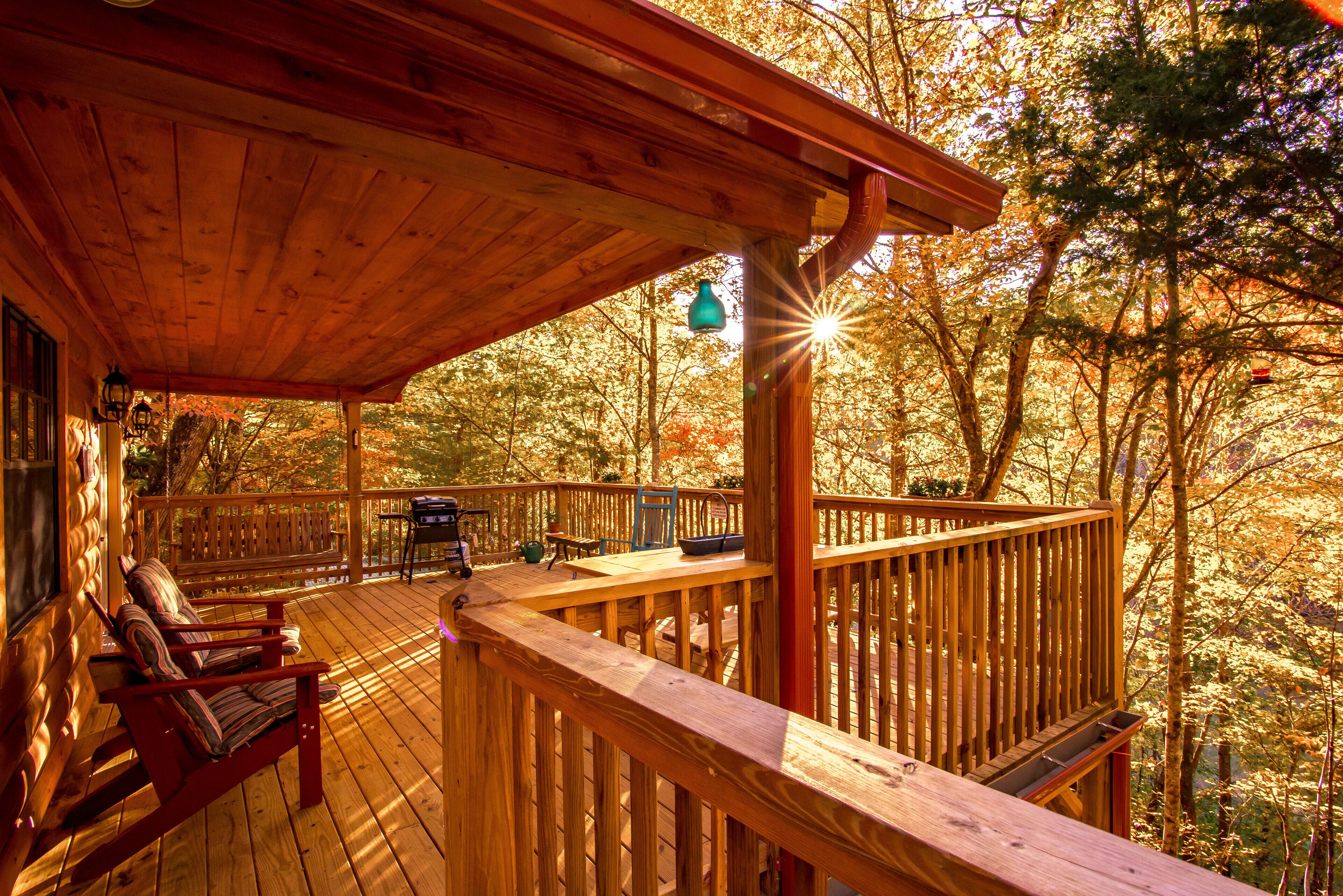 A wooden deck with a covered seating area, a table, and a hanging light fixture.