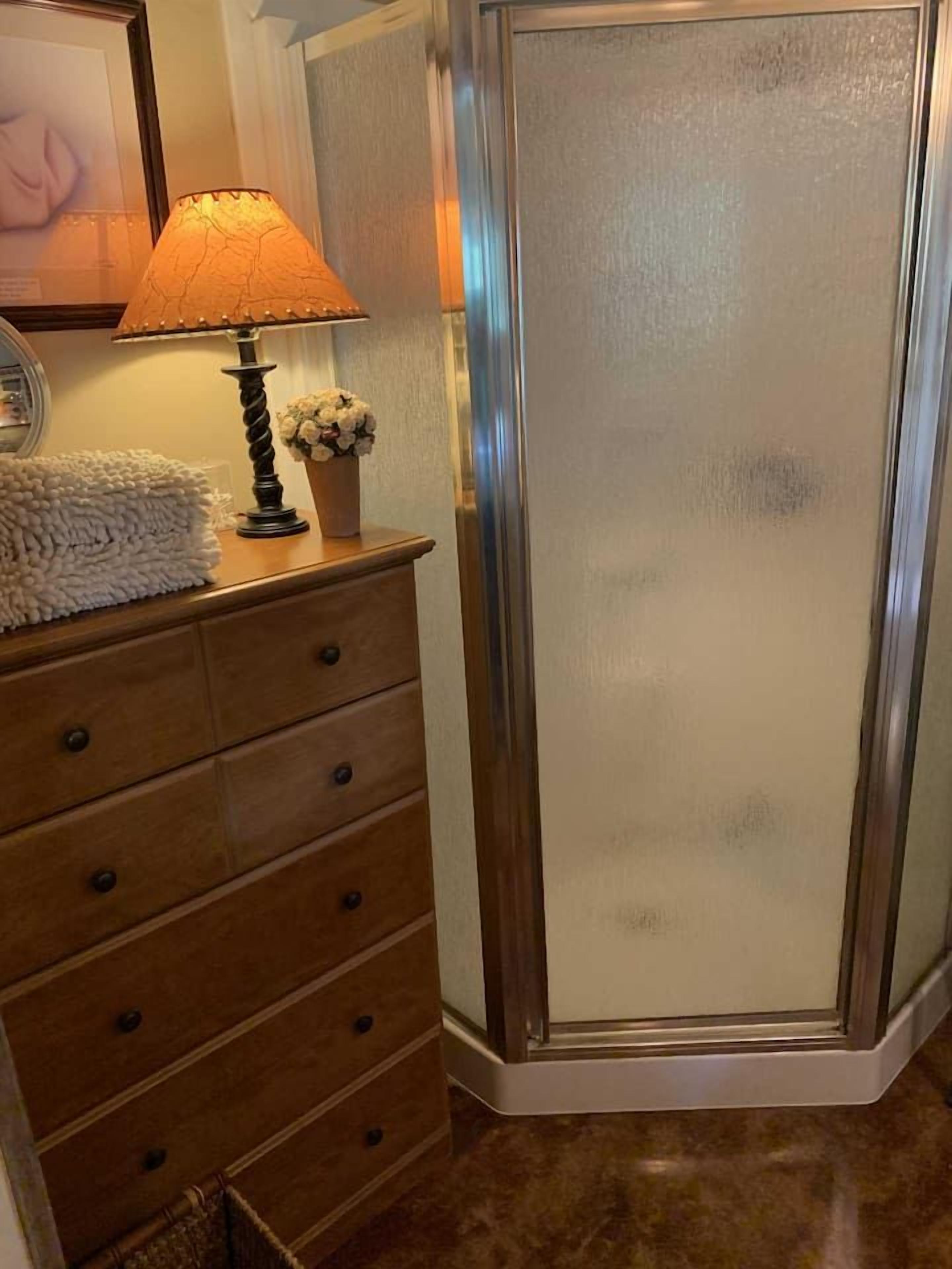 Une commode en bois avec des tiroirs, une lampe et un vase rempli de fleurs.