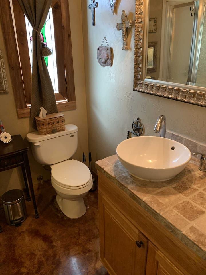 Un baño con inodoro blanco, un lavamanos grande en blanco y un espejo con marco decorativo.