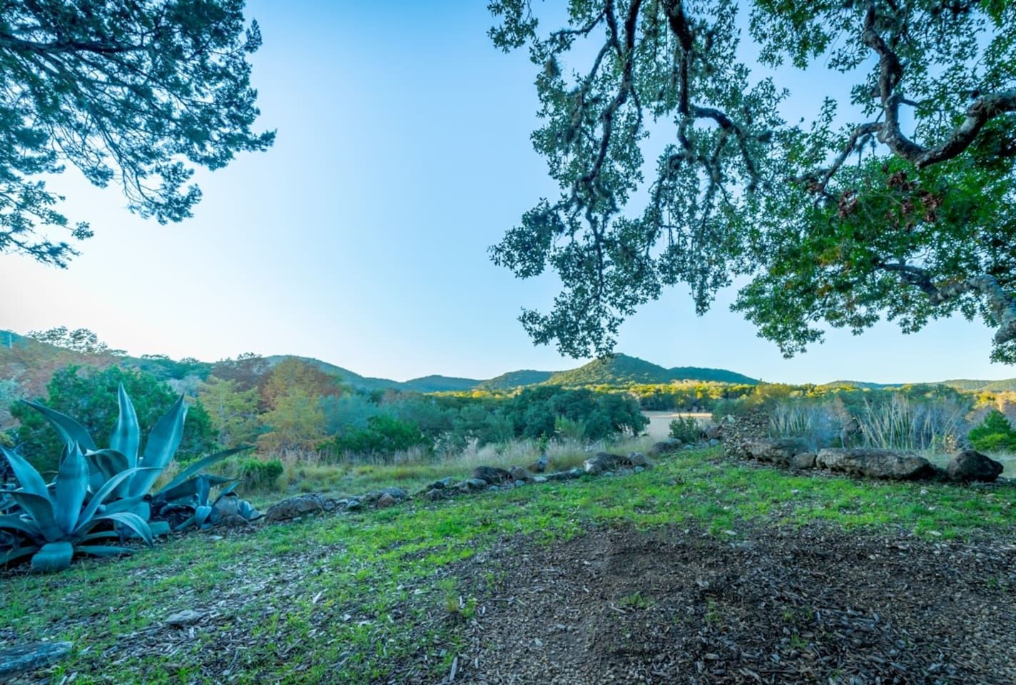 Un paisaje natural con cielo despejado, un río y colinas distantes.