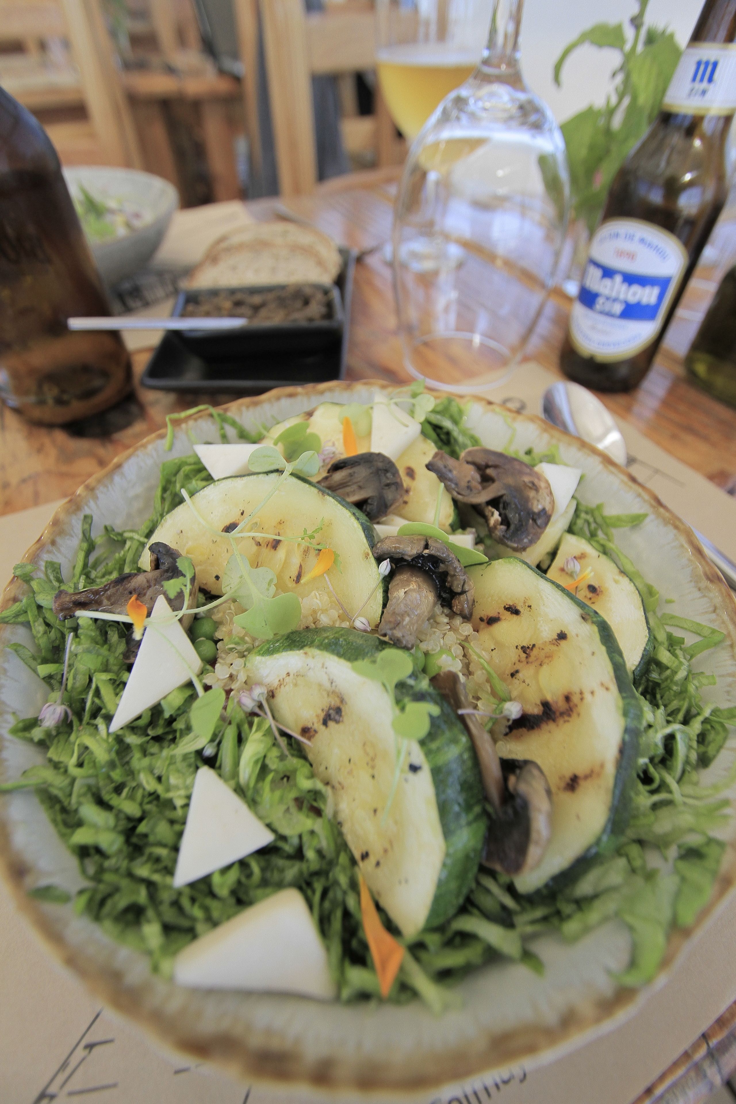 Une assiette de nourriture comprenant une salade, des champignons et des tranches de courgettes.