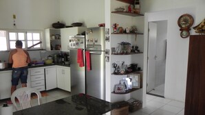 Een keuken met witte kasten, een roestvrijstalen koelkast en een persoon die bij het aanrecht staat.