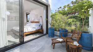 A modern bedroom with a large sliding glass door leading to a balcony with a wooden bench, a small table, and potted plants. - 2BDR 2.5Bath Vacation House w/Private Pool Steps from the Beach (San Francisco)