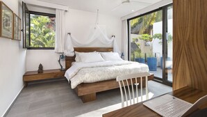 A modern bedroom with a large bed, a laptop on a wooden table, and a view of the outdoors through a sliding glass door. - 2BDR 2.5Bath Vacation House w/Private Pool Steps from the Beach (San Francisco)