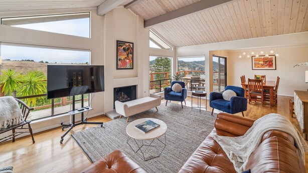 A spacious living room with a large TV, comfortable seating, and a fireplace. - Magnificent Canyon View, Huge Deck, Outdoor Dining (San Rafael)