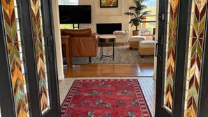 A living room with a fireplace, a television, and a large window. - Magnificent Canyon View, Huge Deck, Outdoor Dining (San Rafael)