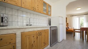 A kitchen with wooden cabinets, a dishwasher, and a refrigerator. - Seafront Apartment Dana - Two Bedroom Apartment with Terrace and Sea View (Vela Luka)