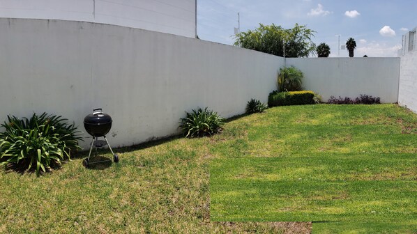 A grassy area with a barbecue grill, a white wall, and some plants. - Beautiful Private house with huge GARDEN (QUERETARO)