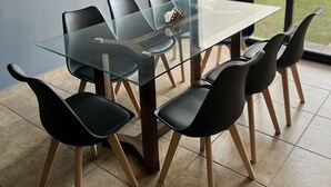 A modern dining area with a glass table and black chairs, featuring pendant lighting and a view through large windows. - Beautiful Private house with huge GARDEN (QUERETARO)