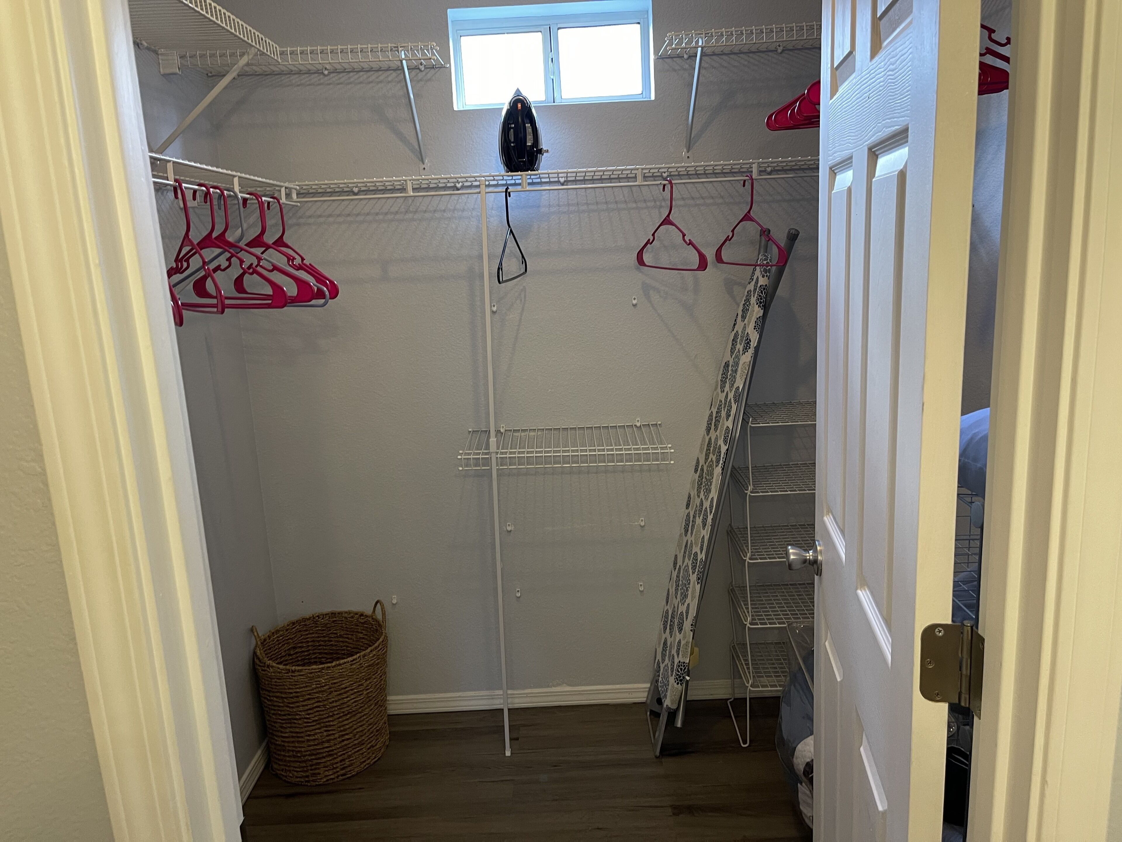 Un dressing avec une étagère métallique, une tringle à vêtements et un panier.