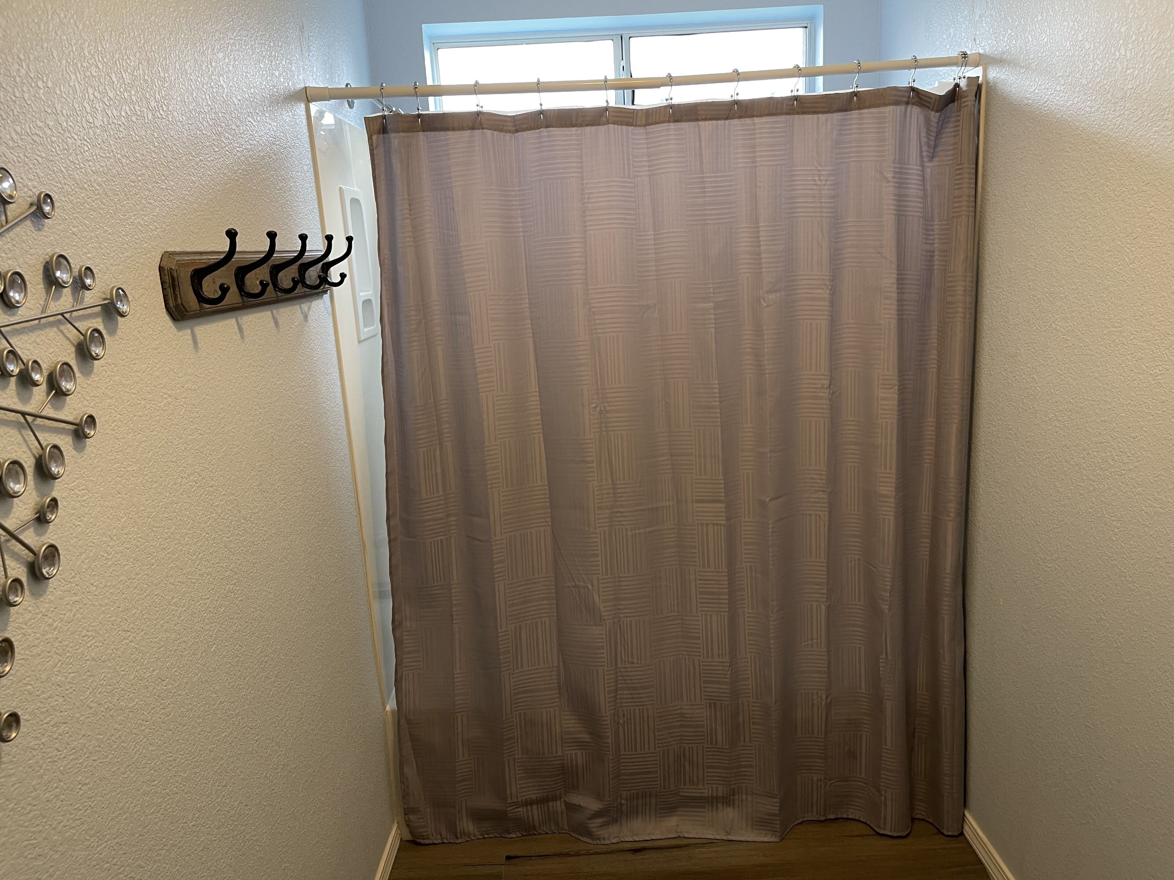 A bathroom with a shower curtain, a towel rack, and a window.