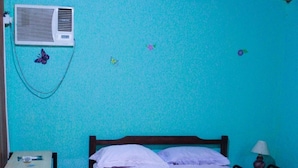 Un dormitorio con cama, escritorio y aire acondicionado en la pared.