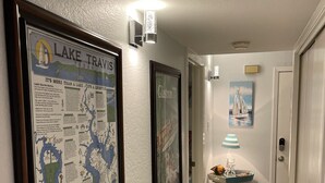 A hallway with framed maps and a small table with a lamp. - Fun N The Sun  Lake Travis Resort 105 (Spicewood)