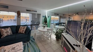A living room with a sofa, a dining table with chairs, a TV, and a fireplace. - Fun N The Sun  Lake Travis Resort 105 (Spicewood)