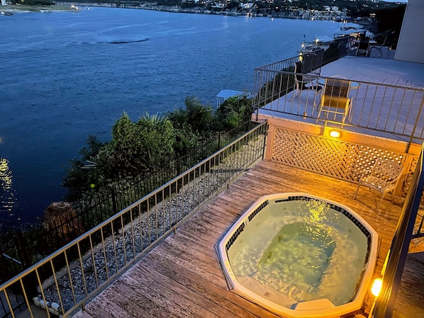 A wooden deck with a hot tub and a view of the sea.