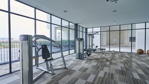 Un gimnasio moderno con amplios ventanales, equipo de ejercicio y una alfombra estampada.