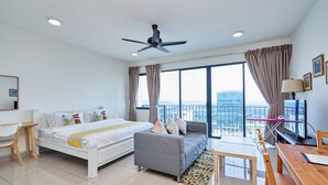 Habitación de hotel moderna con una cama grande, un sofá, una mesa de comedor y un balcón con vistas a la ciudad.