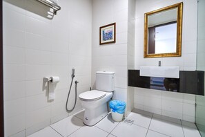 A bathroom with a toilet, a sink, a mirror, and a shower.