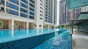 Una piscina con bordes de azulejos, rodeada de edificios altos.
