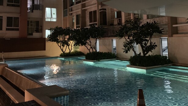 An indoor swimming pool with clear water, surrounded by a wooden deck and potted plants. - Quiet & Secluded Urban Sanctuary for 2 (Bangkok)