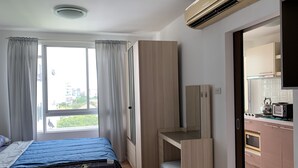A compact bedroom with a bed, a small desk, and a kitchenette. - Quiet & Secluded Urban Sanctuary for 2 (Bangkok)