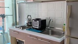 A compact kitchen with a built-in oven, a microwave, and a sink. There are cabinets above the counter and a small window above the sink. - Quiet & Secluded Urban Sanctuary for 2 (Bangkok)