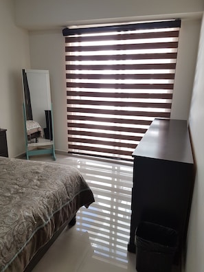 Relax in this serene bedroom with a comfortable bed, dresser, and mirror.