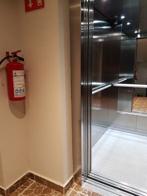 Contemporary hotel room with a modern elevator and safety features.