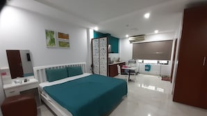 A modern bedroom with a bed, bedside table, and a desk. There is a wardrobe and a bathroom visible in the background. - Vuon Hong Hotel & Apartments (Da Nang)