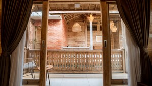 A wooden interior with a brick wall, a hanging light fixture, and a wooden railing. - Rimbun Canggu Villa (Canggu)