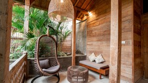 A wooden interior with a hanging chair, a small round ottoman, and a bench with cushions. - Rimbun Canggu Villa (Canggu)