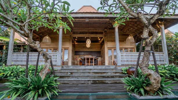 A wooden building with a covered entrance and steps leading to a pool area. - Rimbun Canggu Villa (Canggu)
