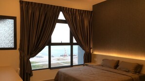 A bedroom with a large bed, a nightstand, and a window with curtains. - Comfort Home Atlantis (Malacca City)