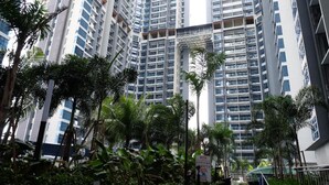 A high-rise residential building with multiple balconies, surrounded by lush greenery and palm trees. - Comfort Home Atlantis (Malacca City)