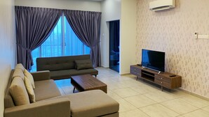 A modern living room with a sofa, coffee table, TV, and curtains. - Comfort Home Atlantis (Malacca City)