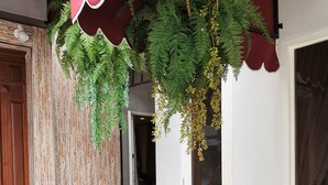 L’entrée d’un hôtel, avec un auvent rouge, des plantes en pot et une fontaine décorative.