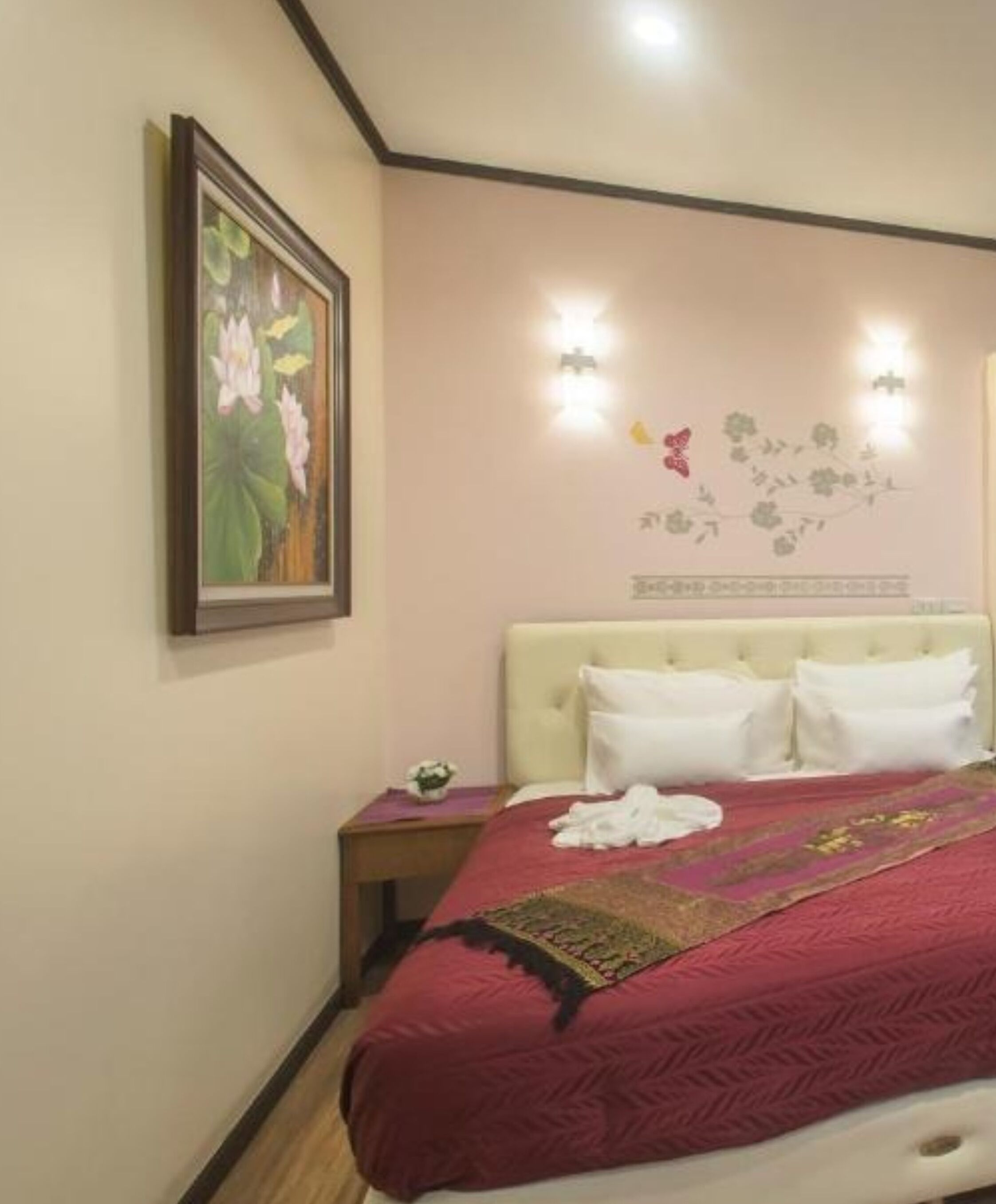 Une chambre d’hôtel avec un lit, une table de chevet, un tableau et des éléments de décoration murale.
