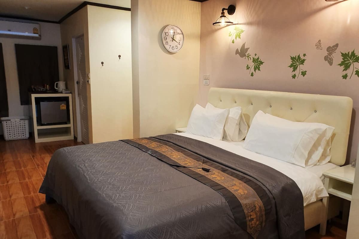 A bedroom with a bed, a clock, and a wall-mounted light fixture.